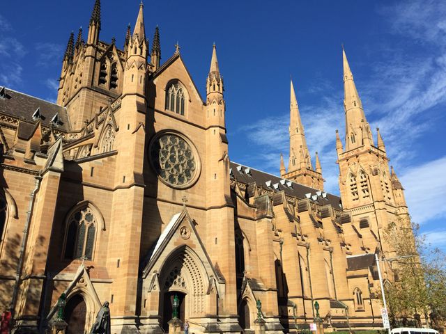 Showcasing exquisite Gothic Revival architecture with prominent spires, this cathedral stands majestically under a clear blue sky. Ideal for travel blogs, architecture studies, historical documentaries, and religious content.