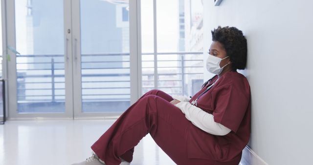 Exhausted Nurse in Scrubs Sitting on Hospital Floor - Download Free Stock Images Pikwizard.com