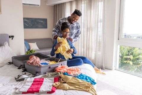 Couple packing luggage on bed in sunlit room preparing for weekend getaway