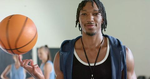 Confident coach spinning basketball in energetic gym training session