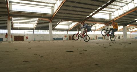 Young Men Performing Stunts on Bicycles in Abandoned Warehouse