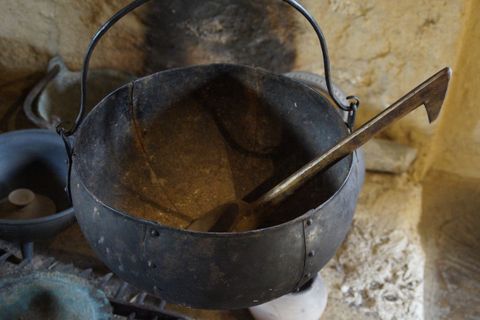 Rustic iron cauldron with wooden ladle in traditional kitchen