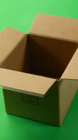 Vertical panning shot inside open cardboard box on green backdrop for product compositing
