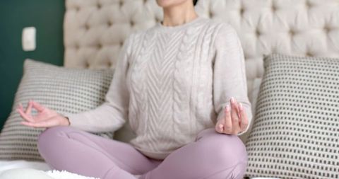 Asian Woman Meditating in Bedroom Promoting Wellness and Tranquility
