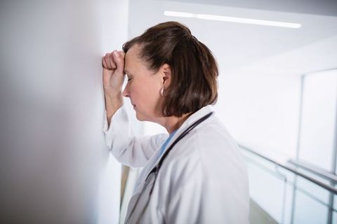 Stressed medical professional contemplating in hospital corridor