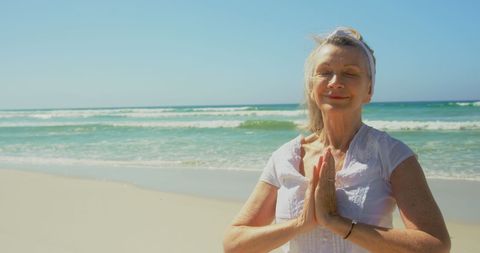 Senior Woman Meditating Wisely on Tranquil Beach