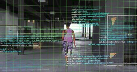 Woman walking through empty industrial corridor with augmented reality grid and code overlay