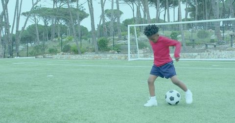 Energetic Boy Dribbling Soccer Ball on Outdoor Field