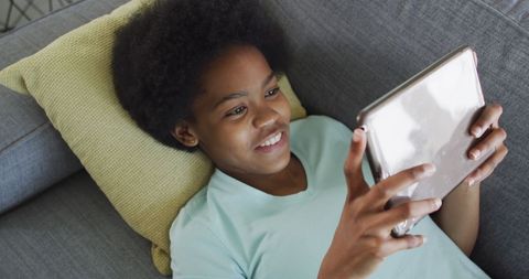 Joyful Teen Girl Relaxing with Tablet on Couch
