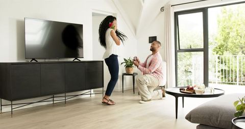 Romantic Home Proposal with Rose and Ring in Bright Living Room
