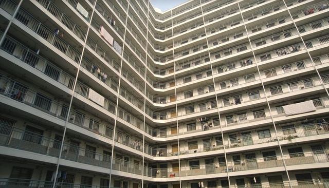 Showing high-rise apartment courtyard with stacked balconies, metal railings and hanging laundry