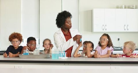 Teacher demonstrating classroom science experiment with young students and blue solution
