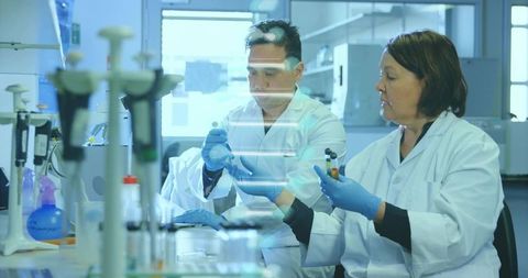 Pipetting and sample handling by lab scientists collaborating at bench in clinical research