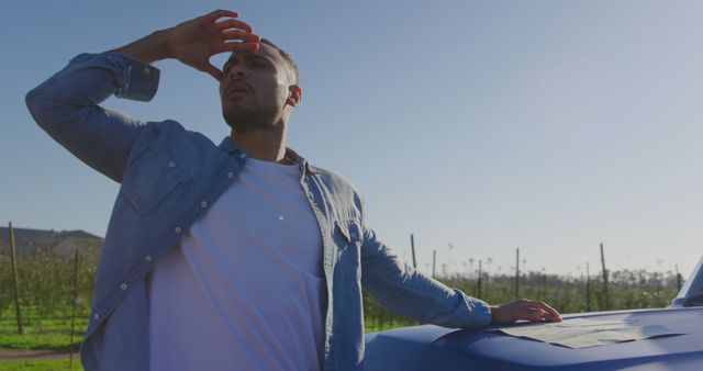 Man Shielding Eyes from Sun Standing by Blue Car in Field - Download Free Stock Images Pikwizard.com