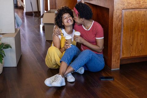 African american lesbian couple kissing and celebrating first home move with coffee