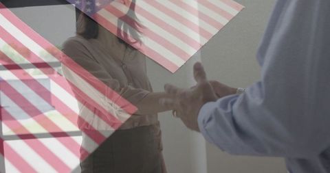 Business partners shaking hands with us flag overlay symbolizing corporate partnership