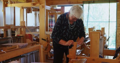 Senior Woman Weaving on Traditional Loom in Craft Studio