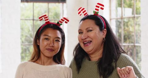 Mother and daughter in cozy knit sweaters with festive candy cane headbands