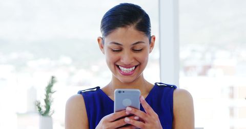 Cheerful Young Woman Enjoying Content on Smartphone Indoors - Download Free Stock Images Pikwizard.com