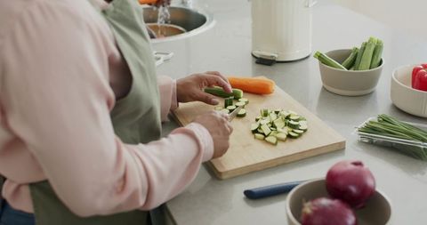Senior couple preparing zucchini and vegetables on kitchen counter for healthy meal prep