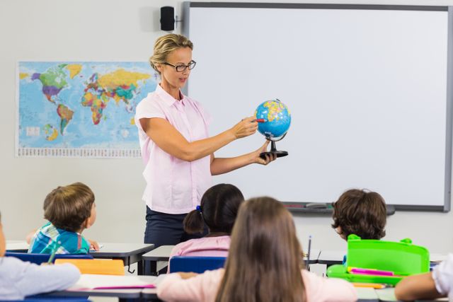 Teacher having lesson with a globe in classroom