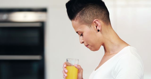 Person Drinking Orange Juice with Modern Hairstyle in Kitchen - Download Free Stock Images Pikwizard.com