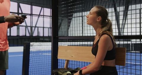Female athlete preparing for padel match indoors with teammate