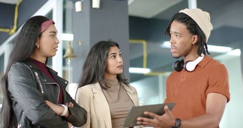 Diverse team discussing project while African American man holding tablet in modern office