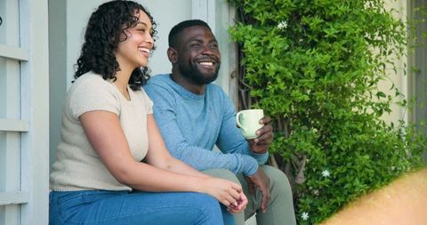 Interracial couple relaxing on porch with coffee