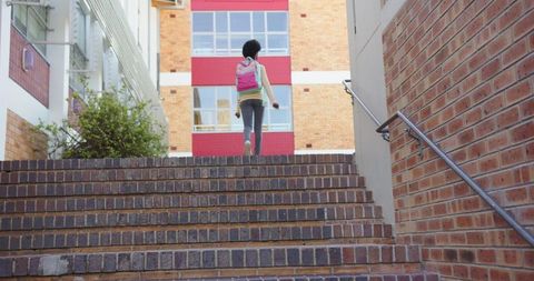 Girl with pink backpack climbing brick school stairs