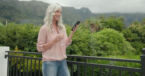 Woman holding smartphone enjoying scenic mountain view outdoors