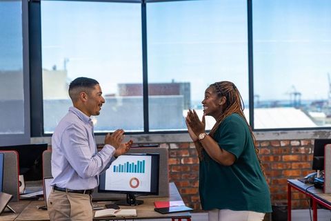 Diverse Coworkers Celebrating in Modern Office with Tech Setup