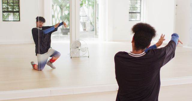 Professional biracial male dancer exercising dance poses alone in dance studio. Activity, lifestyle and dance concept.