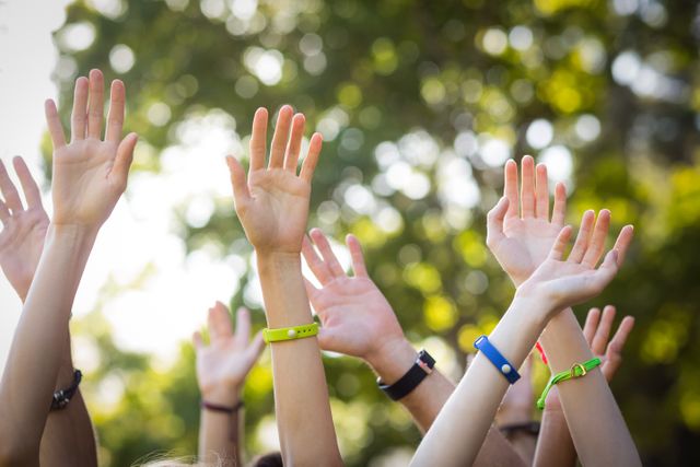 This image captures a group of friends raising their hands while dancing at an outdoor music festival in a park. Ideal for use in promotional materials for music festivals, outdoor events, or summer activities. It conveys a sense of fun, celebration, and togetherness, making it perfect for marketing campaigns targeting youth and event-goers.