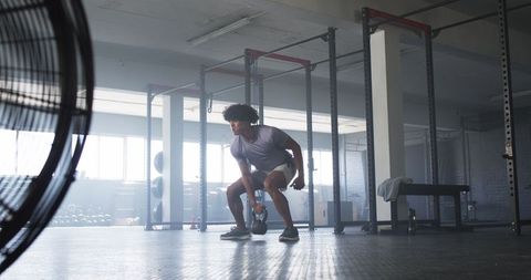 Man Performing Kettlebell Exercise in Spacious Gym