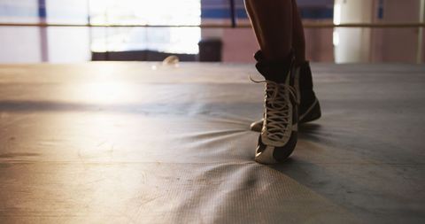 Brown-and-black boxing boots grounding firm on the gym floor highlight focus and readiness in the boxing ring, representing a commitment to fitness and competition. Perfect for sports ads, fitness blogs, training tutorials, and inspirational content related to athletics or boxing training.