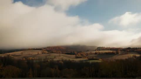 Fog Rolling Over Autumn Hillside with Sunlit Foliage