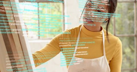 Creative artist-coder tracing virtual code overlay on sunlit studio glass with easel