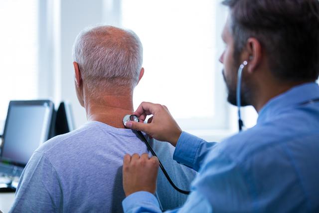 Male doctor conducting a physical examination on an older male patient using a stethoscope. Ideal for use in healthcare, medical, or hospital contexts to depict patient care, diagnosis, and routine health checkups.