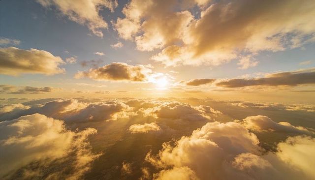 Golden Sunburst Over Sea of Cumulus Clouds at Sunset Illuminating Aerial Landscape