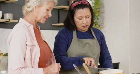 Senior Female Friends Decorating Cake at Home