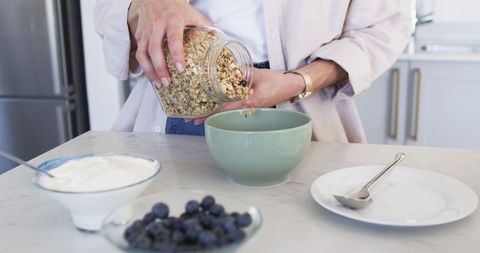 Middle-Aged Woman Preparing Healthy Breakfast with Granola and Berries