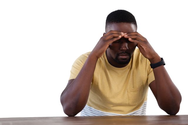 This image depicts a man sitting at a table with his head in his hands, appearing upset and stressed. It can be used to illustrate concepts related to mental health, stress, worry, and emotional struggles. Suitable for articles, blogs, and campaigns focusing on mental well-being, personal challenges, and emotional support.