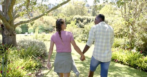 Romantic Stroll of Diverse Couple in Sunlit Garden - Download Free Stock Images Pikwizard.com