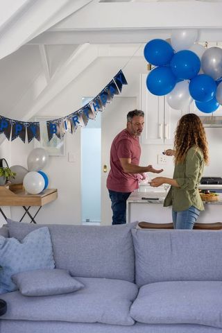 Couple celebrating birthday in cozy loft kitchen with blue balloons and happy banner