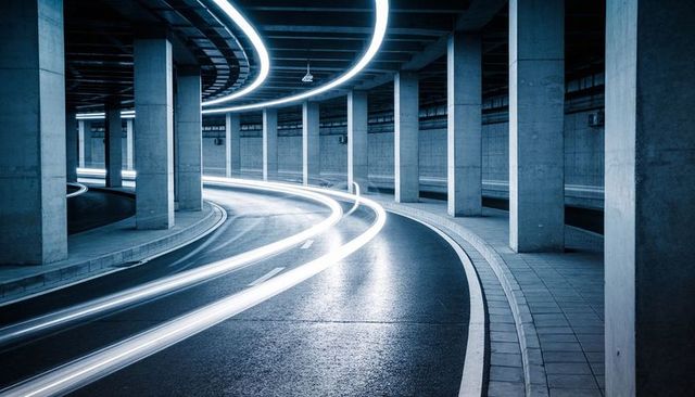 Neon light trails curving through underground concrete ramp with circular ceiling lights