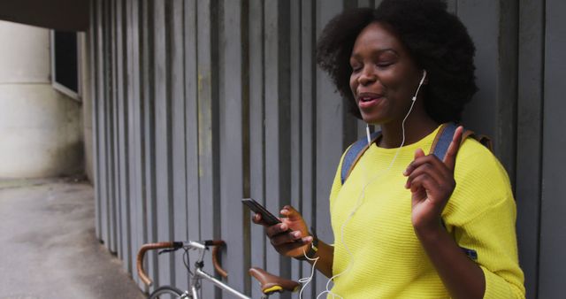 Woman Enjoying Music with Smartphone and Earphones Near Urban Wall - Download Free Stock Images Pikwizard.com