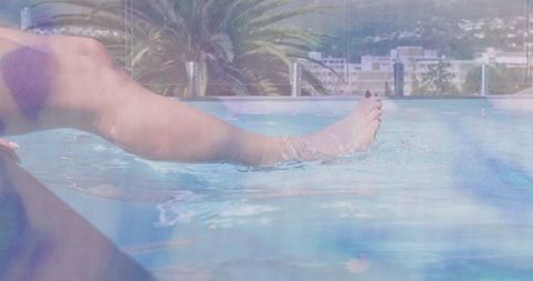 Woman relaxing with toes in rooftop pool under clear skies