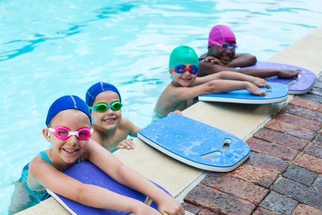 Portrait of little swimmers with kickboards leaning at poolside