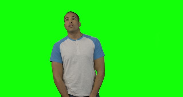 This man wearing a grey and blue henley t-shirt is posing against a green screen backdrop. Ideal for using in various graphic design and video editing projects, including chroma key effects. Useful for presentations, commercials, or any visual content where an isolated image of a relaxed male figure is required.